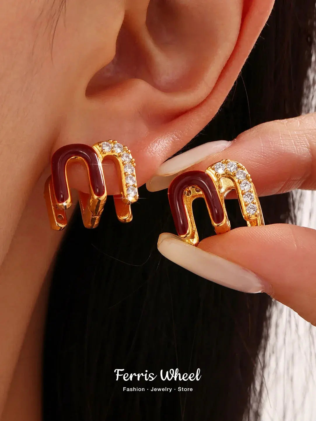 Wine red enamel earrings with gold plating and rhinestone accents on ear